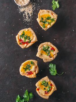 Ideas and recipes for healthy Vegan Shakshouka cups with vegan tofu eggs and turmeric yolk. Puff filo pastry,tomato sauce and green parsley.Top view or flat lay.Copy space for text. Vertical.