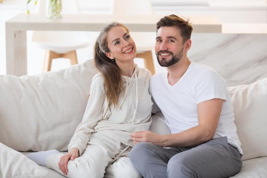 Young beautiful couple smiling sitting on a sofa at home