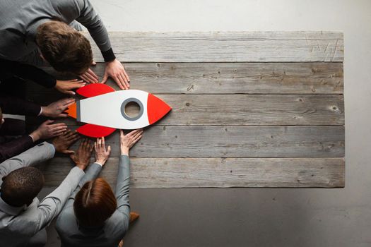 Creative business team sitting at table with startup rocket