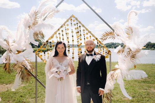 happy wedding couple near the arch during the wedding ceremony.