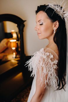 Portrait of the Bride in a wedding dress in the interior of the house near the mirror.