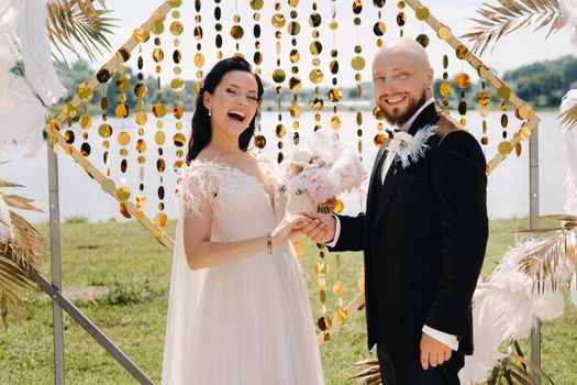 happy wedding couple near the arch during the wedding ceremony.