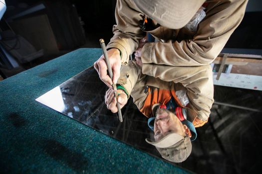 A worker cuts glass with a glass cutter. Furniture manufacturing.