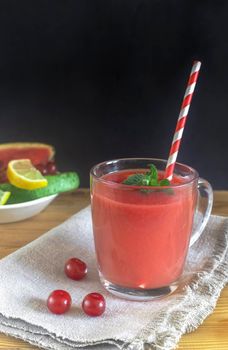 Fresh watermelon juice with cherries and lemon in a glass. Slices of watermelon and cherry berries on the table. Front view. Copy space. The concept of natural nutrition.