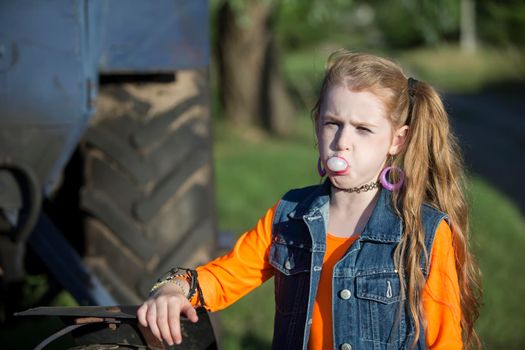 A little girl in bright clothes blew out a bubble of gum.