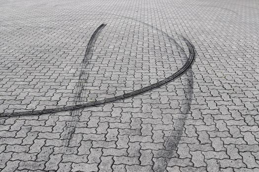 Black tire tracks on a cobblestone road