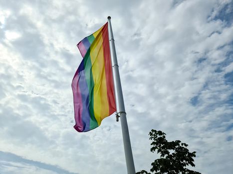 Rainbow pride flag on a flag pole. Lgbt community symbol in rainbow colors. 