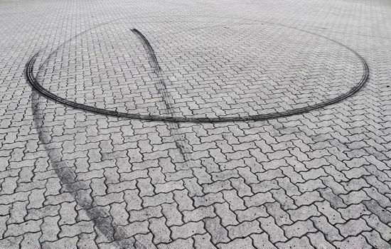 Black tire tracks on a cobblestone road