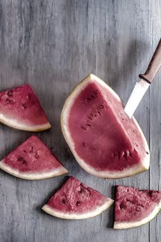 Sliced watermelon slices are lying on the wooden surface of the table. Top view, close-up, copy space