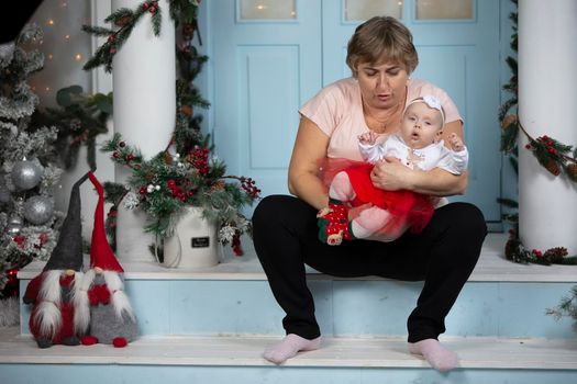 A grandmother in a Christmas photo studio calms her little granddaughter.