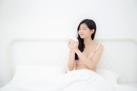 Beautiful young asian sexy woman in underwear drinking coffee in the morning on bed at bedroom, asia girl with seductive figure fit drinking beverage for relax after wake up, lifestyle concept.