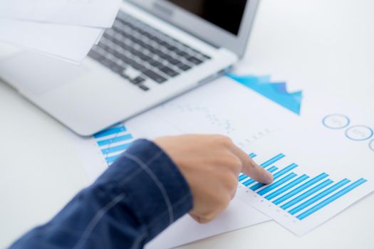 Hand of young business man pointing document data graph and chart paper, marketing and investment, report of statistics profit for financial, economic and growth of finance, management and planning.