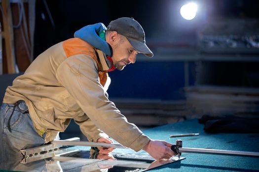 A working person in a furniture industry is cutting a mirror with a glass cutter.