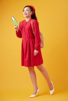 Traveler tourist young beautiful asian woman with backpack, smiling and standing on yellow background. Summer holidays, vacation and travel concept