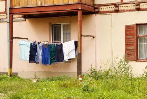 washed clothes are dried on a rope in the yard on summer day