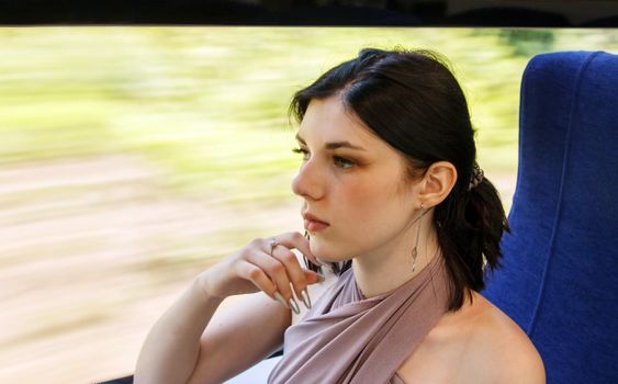 young brunette woman sitting by the window in the train. portrait closeup