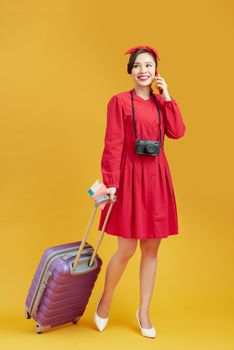 Full length of young female in casual walking with the travel bag, isolated on yellow background