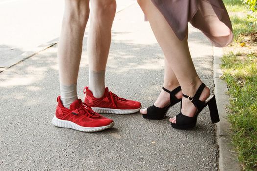 legs of a man and a woman facing each other. standing on sidewalk on summer day