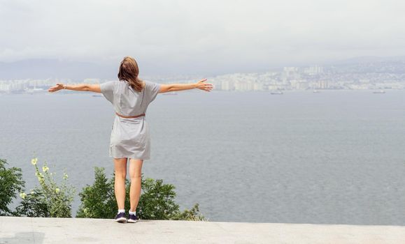 Back view of young woman in summer dress looking at the cityscape. Freedom concept. Travel concept