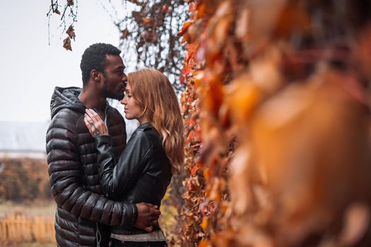 Interracial couple posing in autumn leaves background, black man and white redhead woman