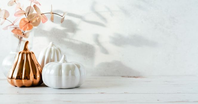 Details of Still life, pumpkins, candle, brunch with leaves on white table background, home decor in a cozy house. Autumn weekend concept. Fallen leaves and home decoration