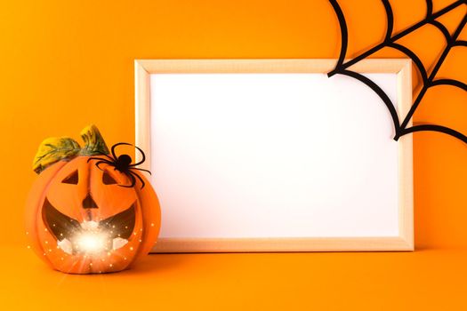 Happy halloween holiday concept. Jack o lantern, handmade paper decorations, spider, web and blank frame on orange background. Halloween festival party, greeting card with mockup copy space.