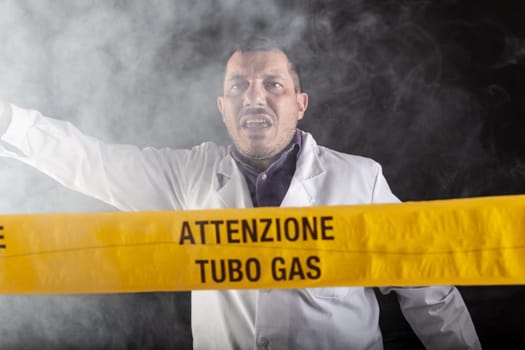 A medical engineer experienced in the gas leaks crisis directing the emergency during the chaos. On the yellow tape the written notice "attention gas tube"