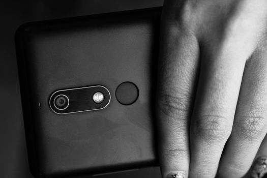 Woman hand holding a black smartphone in her hand. Black smartphone