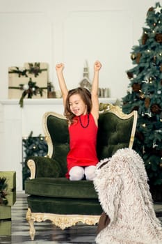 The little girl fell asleep in the living room on an armchair waiting for Santa on Christmas night.