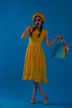 smiling woman in a yellow hat Shopaholic fashion style blue background. High quality photo