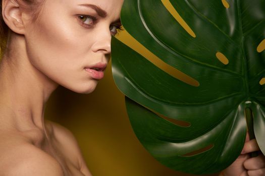 beautiful woman clean skin palm leaf cosmetics yellow background. High quality photo