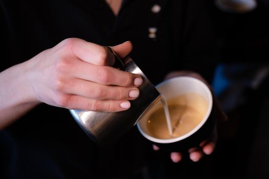 latte art by barista. pouring milk in coffee. dark coffee house.