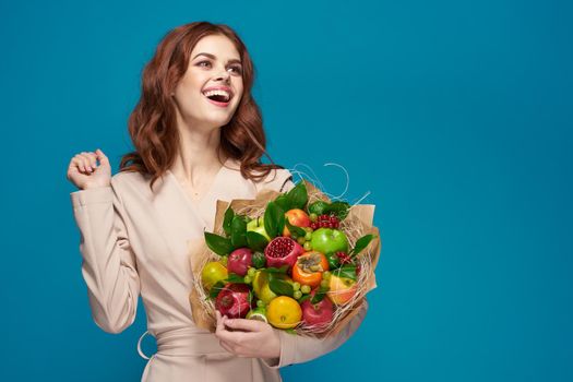 beautiful woman beige coat fruit bouquet in hands blue background. High quality photo