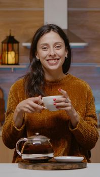 Festive woman talking on video call conference with family in decorated kitchen. Person chatting on online internet communication for christmas celebration on holiday. Merry season