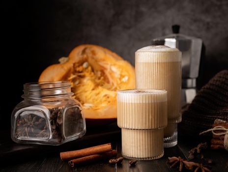 Autumn food and drink. Seasinal drinks. Pumpkin spicy latte with cream and spice, front view, dark background