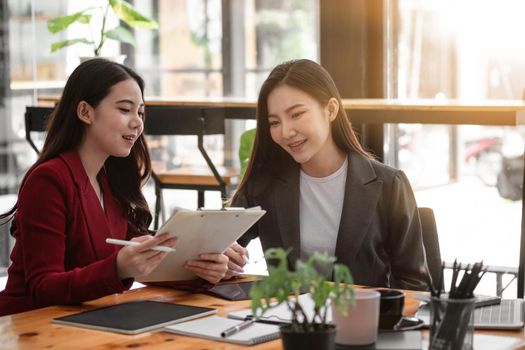 Business People Planning Strategy Analysis from financial document report, two asian female working together at office.