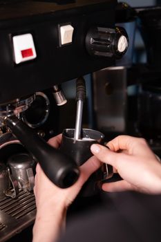 Process of preparing milk foam for cappuccino or latte, heating and whipping. Barista steaming milk in the pitcher