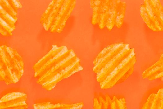 Ribbed potatoes snack with pepper on pastel orange background. Ridged potato chips on orange background. Collection. Flat lay. Close-up.