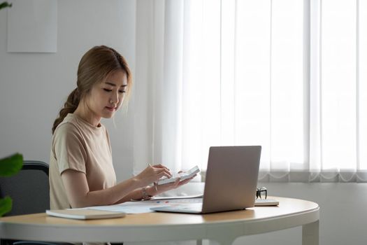 Business woman using calculator with computer laptop, Business accounting, budget and loan paper in office.