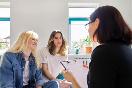 Female teacher talking to two teenage students. Guy and girl 16, 17 years old at the meeting of counselor, mentor. Adolescence, psychology, knowledge, therapy, education, high school, people concept