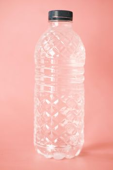 fresh drinking water in a plastic bottle on pink .