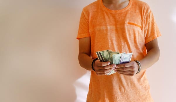 A young tanned man holds money dollars in his hands. Space for copying text