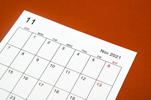 Close up November 2021 calendar sheet on red background.