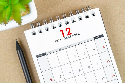 December 2021 desk calendar on wooden table.