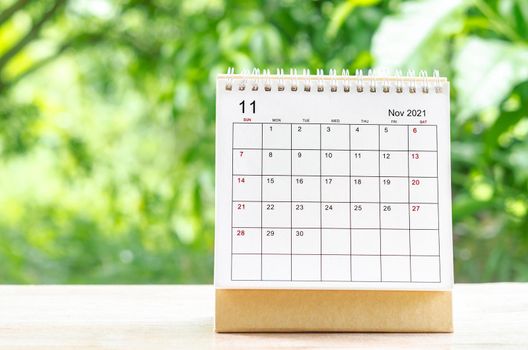 November 2021 Calendar desk for organizer to plan and reminder on wooden table on nature background.