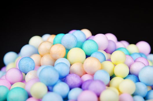 Foam beads of various colors brightly colored on black background.