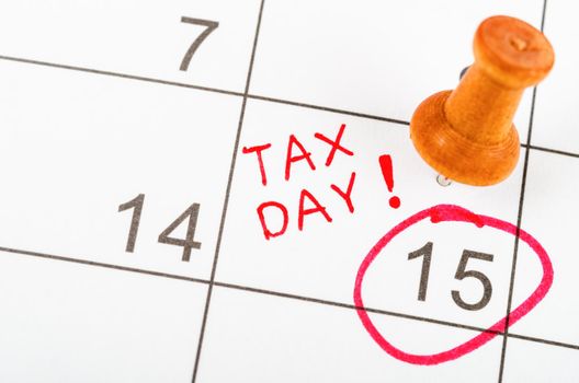 Handwritten Tax day for reminde apointment with wooden pin on a calendar.