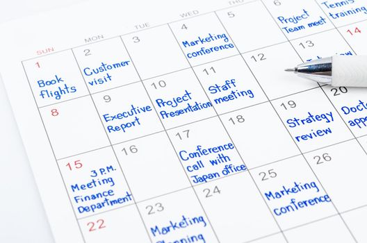 Handwriting scheduling appointments on calendar sheet with pen.