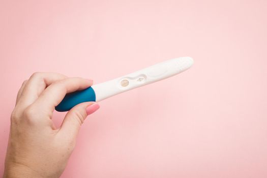 Pregnancy test in hand on a pink background . Positive test. Pregnancy copy space. Motherhood