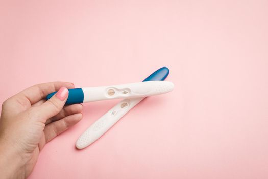 Pregnancy test in hand on a pink background . Positive test. Pregnancy copy space. Motherhood